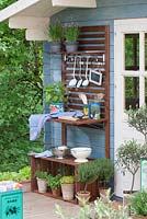 Outdoor kitchen with herbs in pots - including Thymus vulgaris - thyme, Olea europaea, Ocimum basilicum - basil, Allium schoenoprasum - flowering chives, T. citriodorus - lemon thyme 