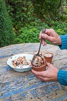 Use a spoon to feed the mix of Lard or Fat, Raisins, Bird seed, Cheese and Peanuts into the terracotta pots