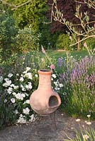 Terracotta chiminea on garden patio with Rosa and Lavender. Bradness Gallery, East Sussex. Owners: Artists Michael Cruickshank and Emma Burnett