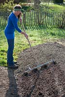 Woman raking compost on newly created bed