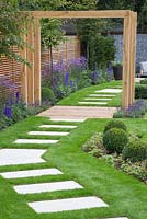 View of the Pergola in the middle of the path, surrounded by Buxus sempervirens cubes, Verbena bonariensis, Delphinium elatum 'Blaustrahl', Geranium 'Johnson's Blue' and Lavandula angustifolia 'Hidcote'