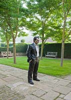 The Figaro garden with lawn and paving.  Bronze by Sean Henry 'Standing Man' 