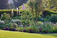 Lawn and border with Eremurus, Alliums and Berberis.  Champagne tent beyond. Summer 