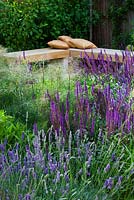 Formal town garden with wooden corner bench and cushions with planting including Salvia mainacht, purpurescens. Designer: Charlotte Rowe, London