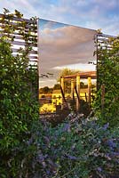 Roof garden - bronzed glass mirror on trellis wall with cityscape and sky reflections. Designer: Charlotte Rowe, London
