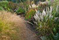 Path through borders. Piet Oudolf garden Hummelo. Sporobolus heterolepsis, Helenium Moerheim Beauty, Calamagrostis brachytricha