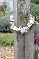 Chain of pebbles around wooden post with house number 