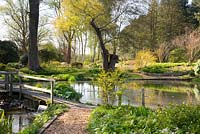 Unstructured country garden with wooden bridge over mill pond sluice