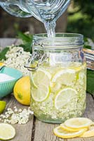 Making an Elderflower drink. Adding water to the mix of sliced Lemon, Lime, Sugar and Elderberry flowers