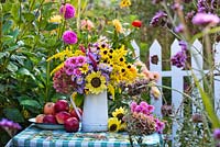 Floral and harvest display of asters, echinacea purpurea, persicaria 'Firetail', sunflowers and apples.