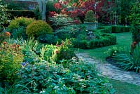 Path beside shady borders of Lamium Cotinus box Buxus topiary in urn container