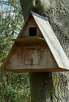 Wooden A-frame barn owl box fixed on a tree at The Place For Plants, Suffolk