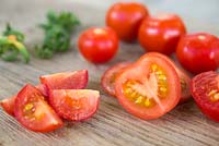 Whole, sliced and halved Tomato 'Gardeners Delight' on chopping board