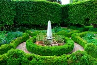 Carpinus hedge  - Pleached hornbeam surrounding parterre garden of box hedging with brick path and a central obelisk surrounded by terracotta container collection