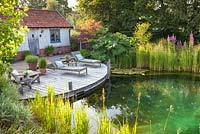 Tranquil summer scene with swimming pond, recliners and decking. 