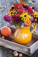 Autumn flowers in pottery vase including cosmos, asters, rudbeckias and chrysanthemums
