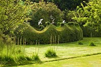 Seagull sculptures of stainless steel fly over topiary Buxus - Box hedges clipped into wave crests. Farleigh House, Hampshire. Designer Georgia Langton. Seagulls by Diane Maclean