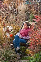 Woman relaxing and drinking tea in autumn garden.