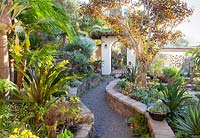 Pathway through walled borders to gateway. Jim Bishop's Garden. San Diego, California, USA. August.