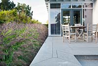 Relaxing area on a patio bordered with Pennisetum alopecuroides 'Cassian'. Van de Voorde garden. Design: Tom de Witte