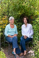 Carol Gould, with her daughter, Kate Gould, award winning British garden designer. Sitting in an arbour clad in clematis, in the garden that Katie designed some years ago for her parents.