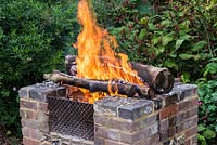 A raised brick fire pit warming the garden in late summer.