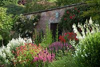 A section of the East border in the Walled Garden at Holehird Gardens Cumbria showing the sun clock above the entrance to the Potting shed