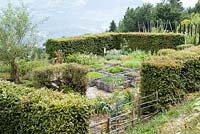 Formal herb garden, with planted squares woven around the sides, sheltered by hedges Jardin des Cimes, Chamonix. France. July 