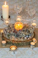 Candle lit festive table decoration made from dried  allium, roses, echinops, sea holly, hydrangea, statice and seedheads of coneflowers, poppies and nigella.