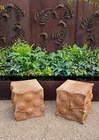 Two carved oak cube wooden seats on gravel path, rusted steel fern wall panel, reflective water feature, planting of ferns, hosta, Constraining Nature garden - designed by Kate Durr Garden Design - Best Festival Garden award and a gold medal - RHS Malvern spring festival 2015