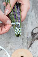 Making a lavender wand step by step. Take the long length of ribbon from the top, and weave it under and over the stems to create a ribbon casing for the flowers.
