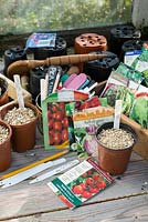 Springtime potting bench scene with pots of freshly sow seeds, seed packets, labels and other gardening items.
