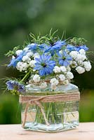 A summer posie of Nigella damascena - Love in the mist and baby's breath in a glass jar decorated with twine.