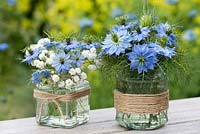 Posies of Nigella damascena - love in the mist and baby's breath in glass jars decorated with twine.