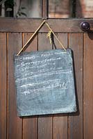 Blackboard with list of jobs to do hung up on greenhouse door