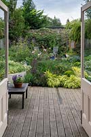 A small walled town garden, 50ft x 40ft, with deck, mixed borders of flowers, vegetables and patio seating area.