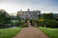 View of Mannington Hall at sunrise with wrought iron bridge over moat. 