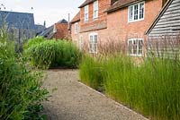 The front garden was designed by Christopher Bradley-Hole on a grid pattern, with tall grasses and subtle flowering perennials to give a contemporary meadow feel. Bury Court Barn, Bentley, Hants, UK