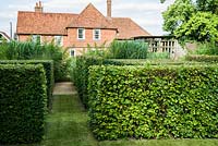 The front garden was designed by Christopher Bradley-Hole on a grid pattern, with tall grasses and subtle flowering perennials in its centre and hornbeam hedges forming a screen from the adjoining track. Bury Court Barn, Bentley, Hants, UK