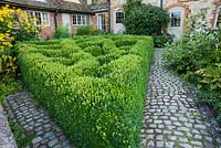 The Courtyard Garden designed by Piet Oudolf and John Coke features a trellis pattern of clipped box in one corner. Bury Court Barn, Bentley, Hants, UK