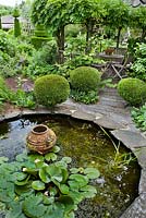 Circular pond with water plants and ornamental urn.
