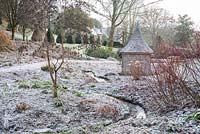 Dormant bog garden with an icing of snow around a wooden summerhouse.