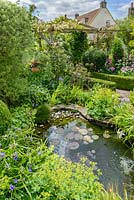 Ornamental pond with access for amphibians. Box topiary and edging. Herbaceous perennials including tradescantia, alchemilla, astrantia and irises. Shrubs include Pittosporum and Ilex crenata.