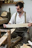 Charlie Groves making a traditional Sussex trug. Testing the flexibilty of a willow board, shaved at either end, and ready to curve into trug body.