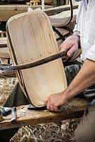 Charlie Groves making a traditional Sussex trug. Using a knife to cut off the excess willow board projecting above the trug rim.