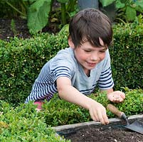 Oscar Isaac, 9, scatters seeds into his vegetable patch.