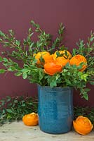 Flower heads crafted from orange peel, accompanied with Eucalyptus in a blue vase