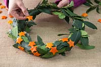 Weave the threaded orange stars around the Laurel wreath with a spiral effect
