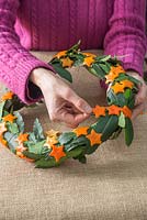 Weave the threaded orange stars around the Laurel wreath with a spiral effect