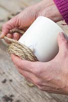 Carefully wrap the rope around the pot, using your spare hand to hold the rope in place